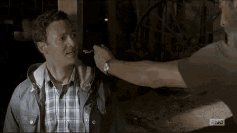 a man is being fed with a spoon by another man .