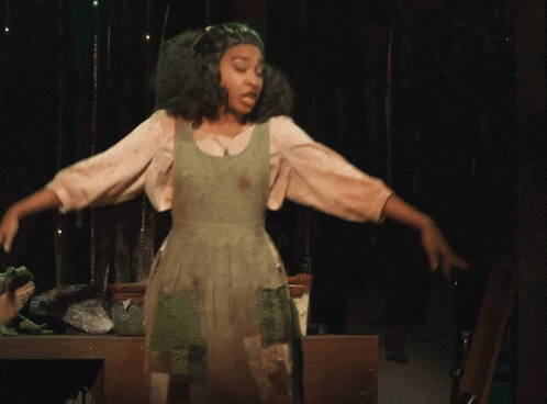 a girl in a green dress is dancing on stage