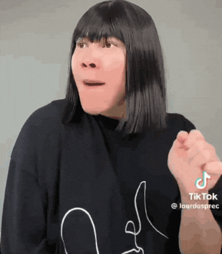 a woman is wearing a black shirt with a drawing of a face on it and a tik tok sticker on her wrist