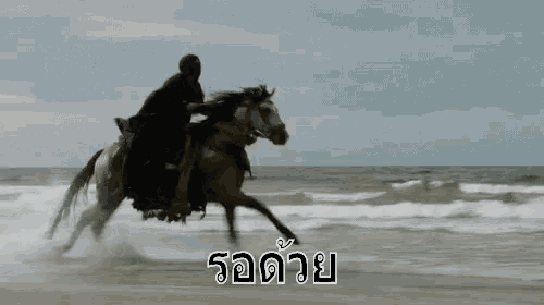 a man is riding on the back of a horse on the beach .