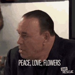 a man is saying peace , love , flowers in a gif .