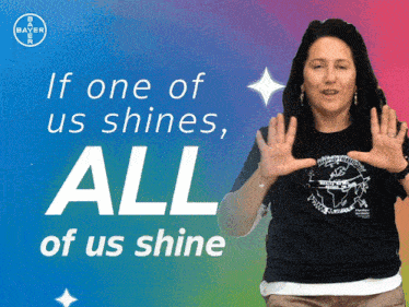 a woman stands in front of a banner that says if one of us shines all of us shine