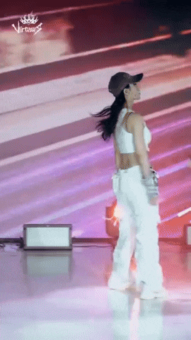 a woman wearing a hat and white pants is dancing on stage