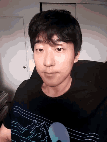 a young man wearing a black t-shirt with a circle on it