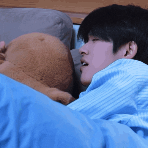 a man in a blue striped shirt is sleeping with a stuffed animal