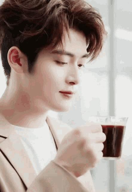 a close up of a man holding a cup of coffee .