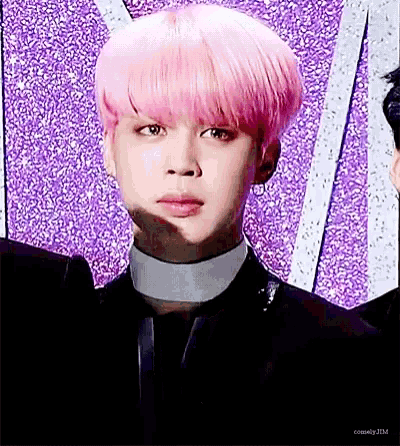 a close up of a person with pink hair wearing a black suit and collar .