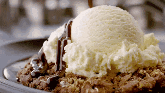 a scoop of vanilla ice cream sits on top of a brownie with chocolate sauce