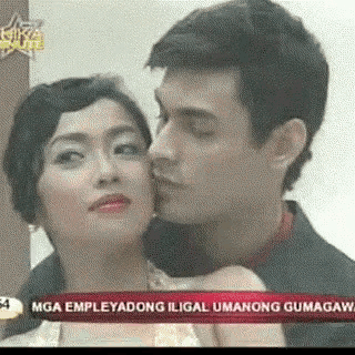a man is kissing a woman on the cheek in front of a banner that says mga empleyadong iligal umanong gumagawa