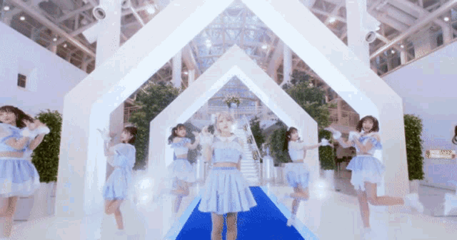 a girl in a blue dress is surrounded by other girls in white