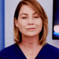 a close up of a woman 's face with her eyes closed and a blue shirt on .