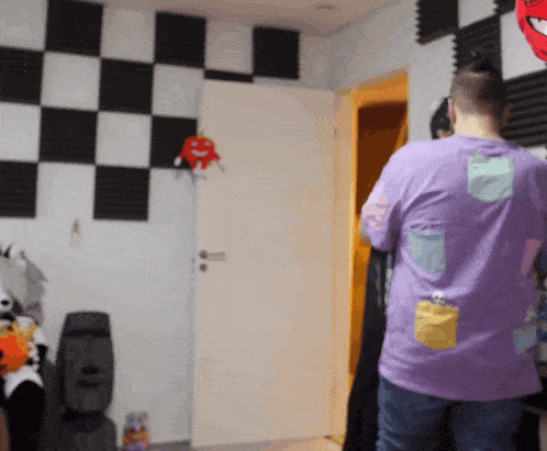 a man in a purple shirt is standing in a room with checkered walls
