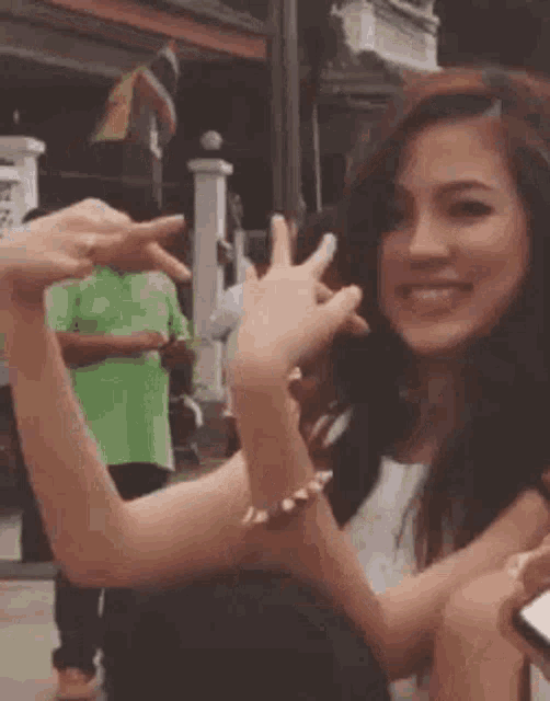 a woman is making a peace sign with her hands while another woman takes a picture of her .