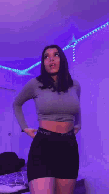 a woman with a nose ring is standing in front of purple lights .