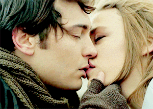 a man and a woman are kissing and the woman is touching the man 's face