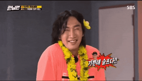 a man wearing a flower lei and a pink shirt is smiling .