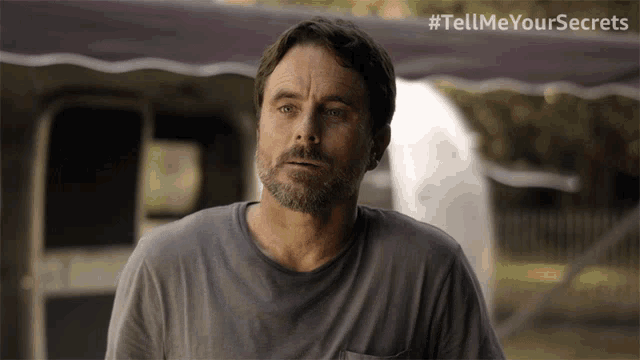 a man with a beard is standing in front of a trailer with the hashtag tellmeyoursecrets