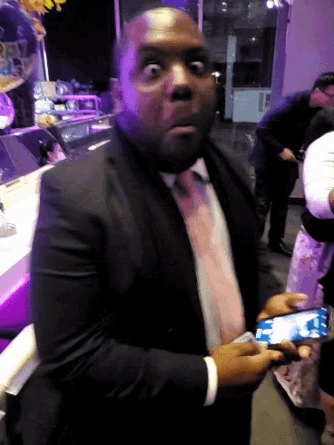 a man in a suit and tie holds a cell phone in his hands