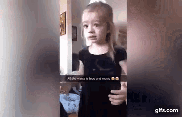 a little girl is making a funny face while holding a cell phone in her hand .