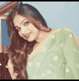 a woman with long hair is wearing a green polka dot dress and smiling .