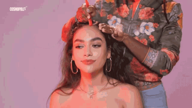 a woman is getting her hair done by a hairdresser in a floral shirt .