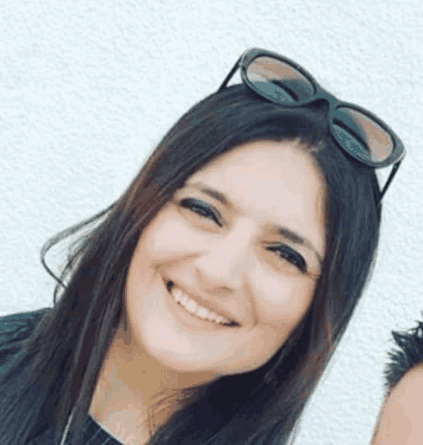a woman wearing sunglasses and smiling for the camera .
