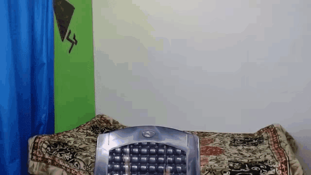 a dell keyboard is sitting on a bed in front of a green and blue wall