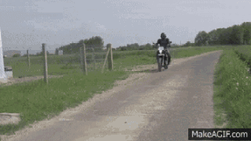 a man riding a motorcycle down a dirt road