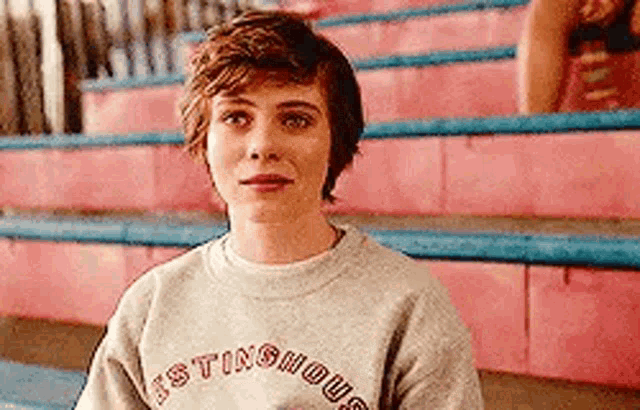 a young woman wearing a sweatshirt is sitting on a set of pink stairs .