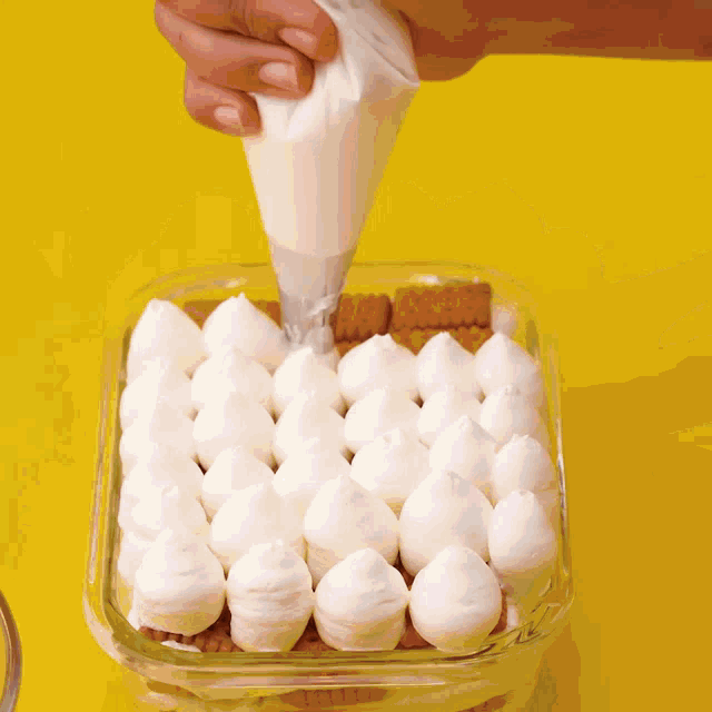 a person is piping whipped cream on top of a glass container