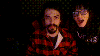 a man in a red plaid shirt and a woman in glasses are looking at the camera