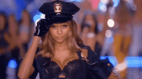 a woman dressed as a police officer is walking down the runway at a fashion show .