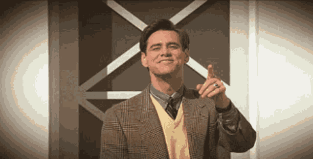 a man wearing a plaid suit and a yellow sweater is pointing