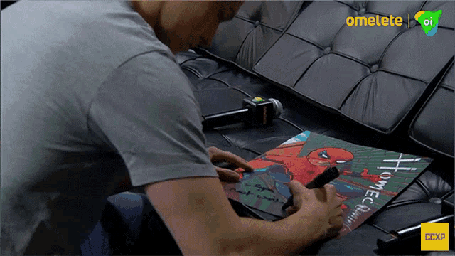 a man sits on a couch writing on a piece of paper that says homecoming on it