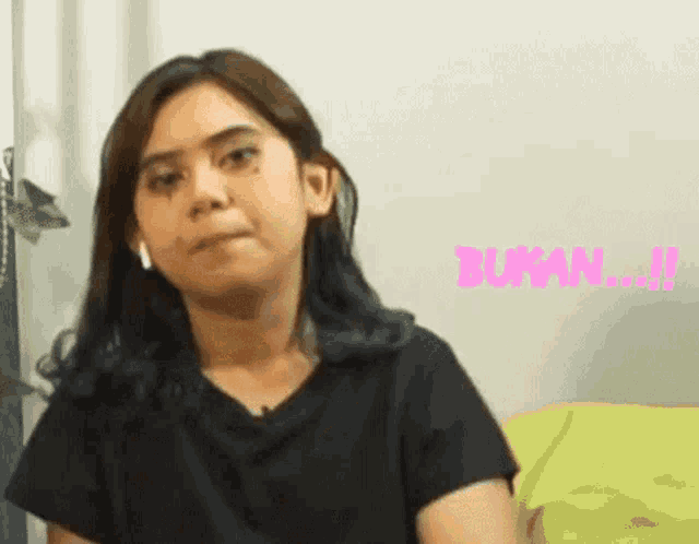 a woman wearing headphones and a black shirt is making a funny face while sitting on a couch .