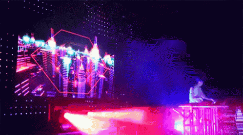 a man is playing a dj set in front of a large screen with a city in the background