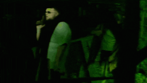 a blurry picture of people in a dark room with a green light behind them