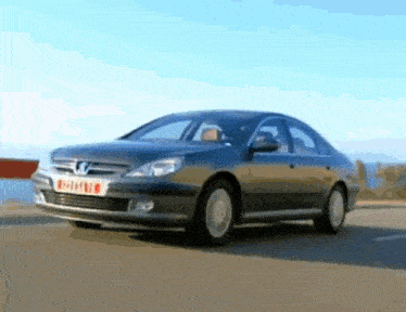 a peugeot car is driving down a road near the water