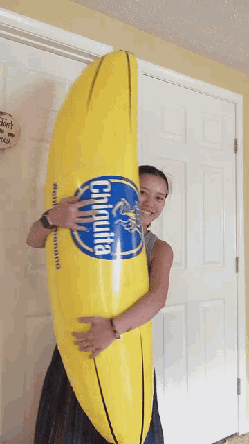 a woman holds a large inflatable banana that says chiquita on it