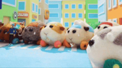 a bunch of stuffed animals are sitting on a blue floor in front of buildings