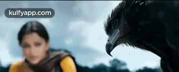 a woman is standing next to a large bird with a large beak .