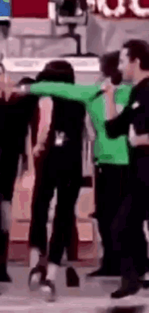 a man in a green shirt is carrying another man in a black shirt .