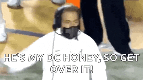 a man wearing a mask and headphones is standing on a football field .