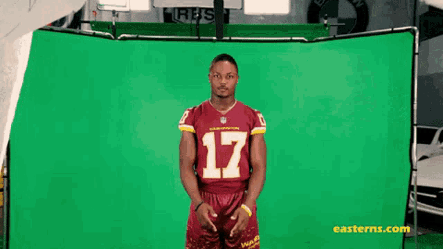 a man wearing a red jersey with the number 17 on it stands in front of a green screen