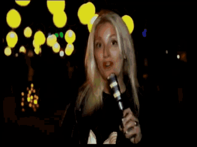 a woman with blonde hair is dancing in a dark room with yellow lights