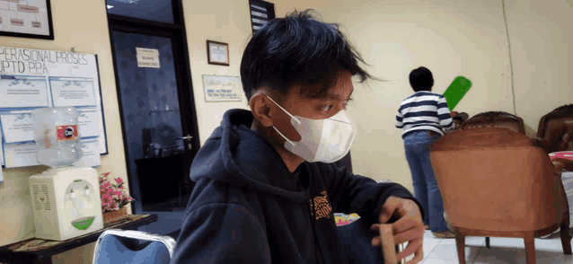 a man wearing a mask is sitting in front of a sign that says personal proses