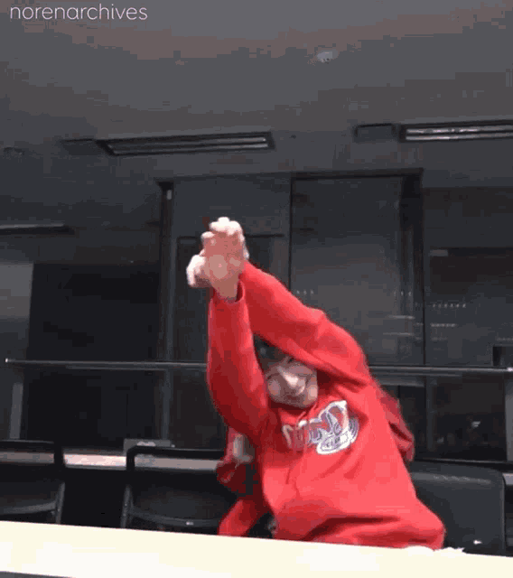 a person wearing a red sweatshirt that says norenarchives on it