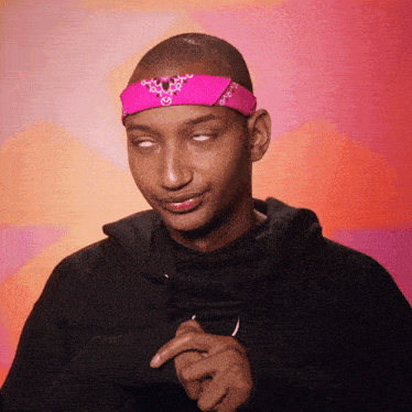 a man wearing a black hoodie and a pink bandana on his head is making a funny face