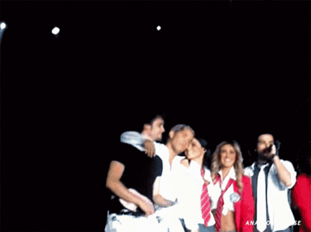 a group of people standing on a stage with the word amigos on the bottom right