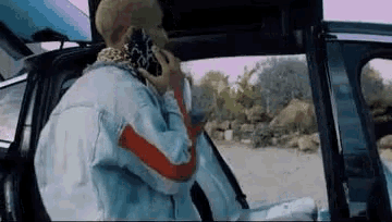 a man is talking on a cell phone while sitting in the back seat of a car .